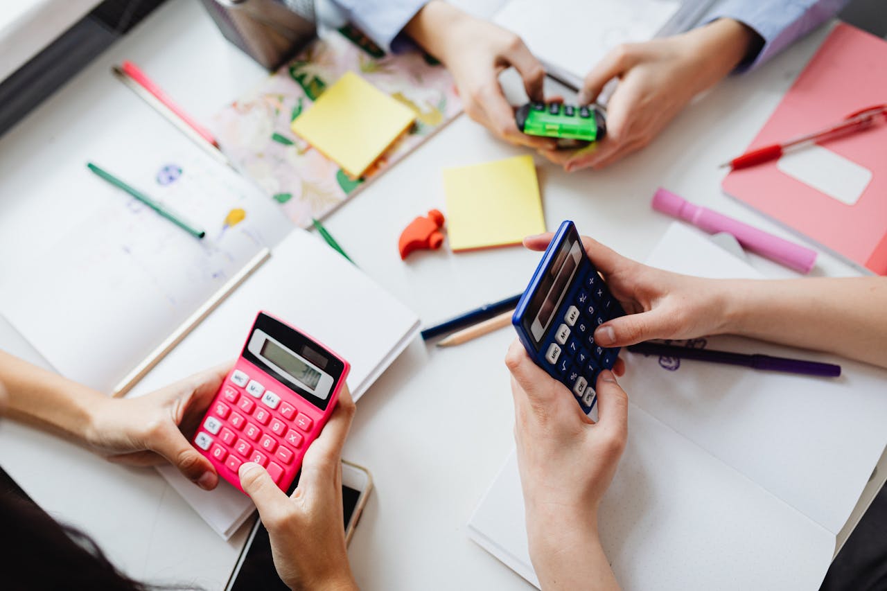 Children using vibrant calculators to solve math problems at school desk.
